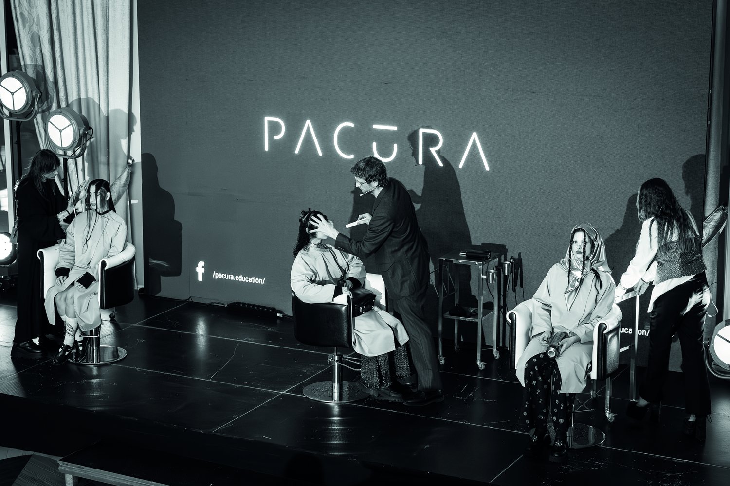 Kristof Pacura podczas pokazu na scenie — kadr czarno-biały z neonem PACURA